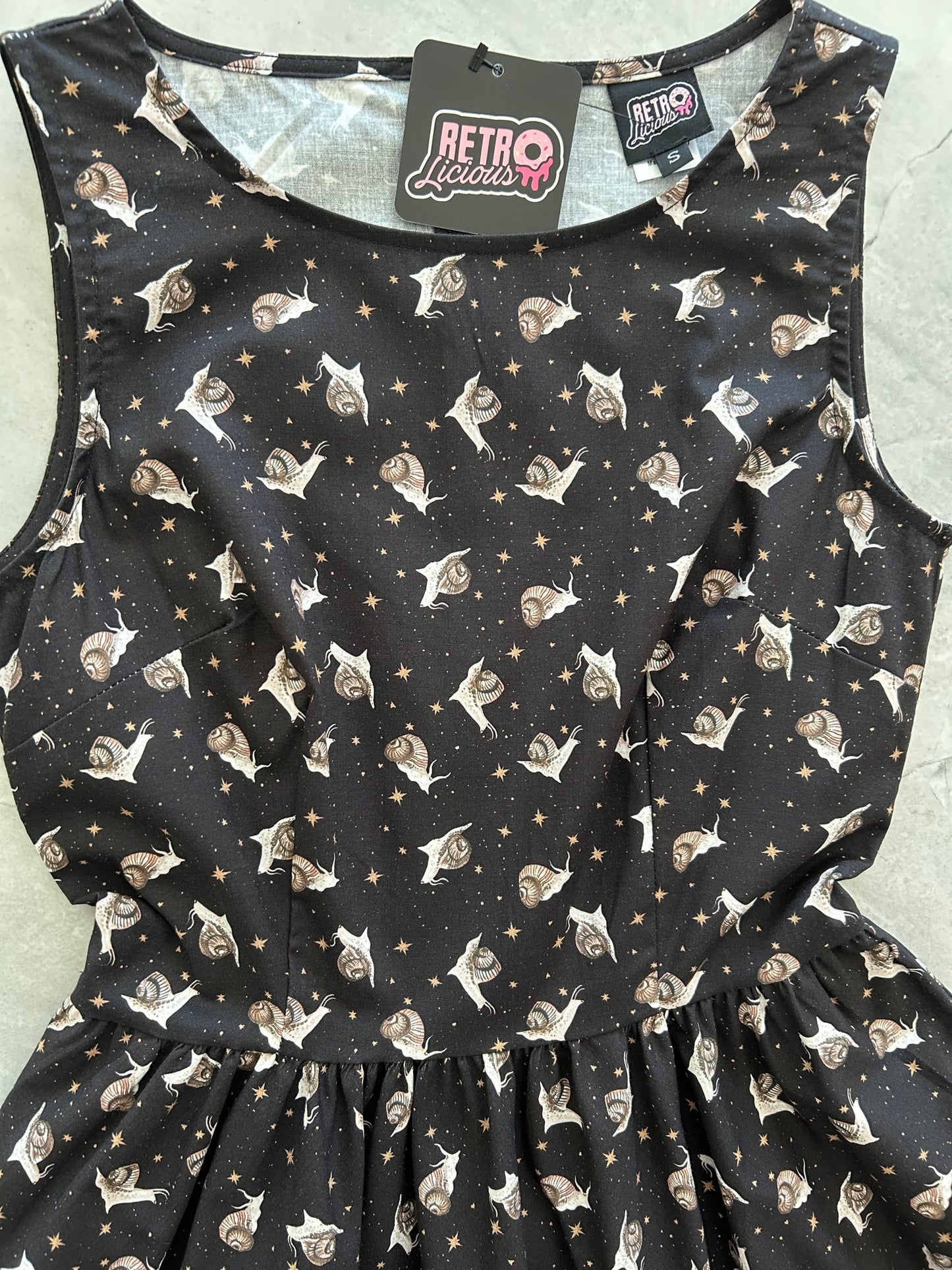 flat lay image of the bodice of our black dress wtih creme snails and gold stars