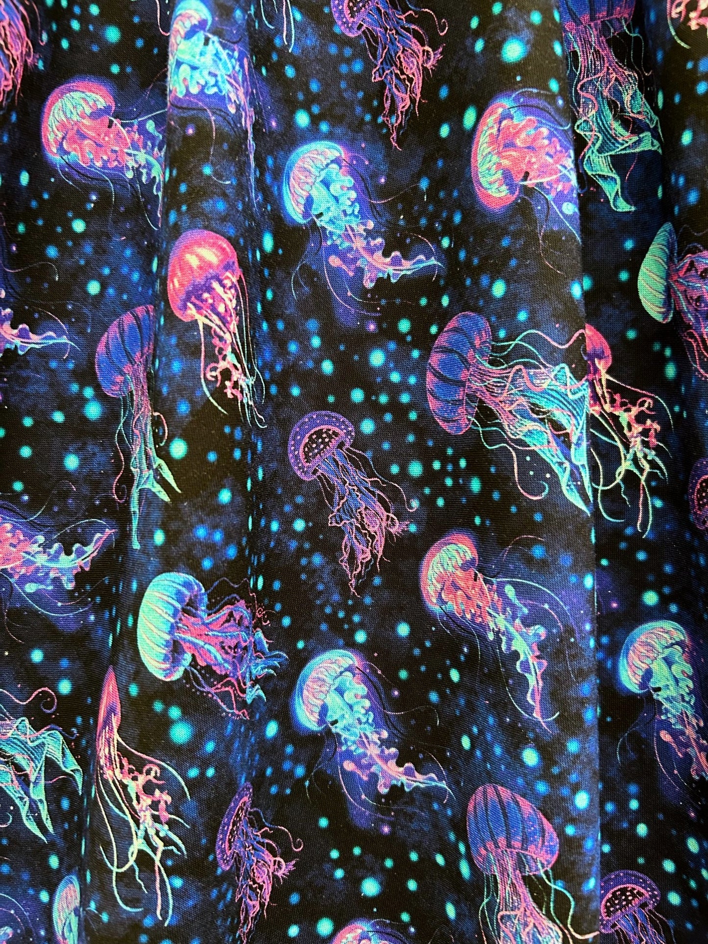 flatlay of jelly dress fabric showing the pink, blue and purple jellyfish