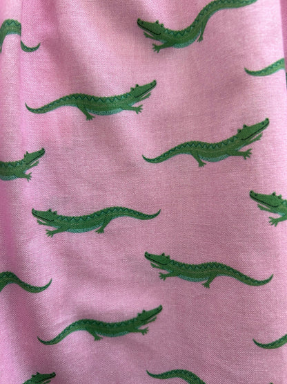 close up of fabric with green alligators on pink background
