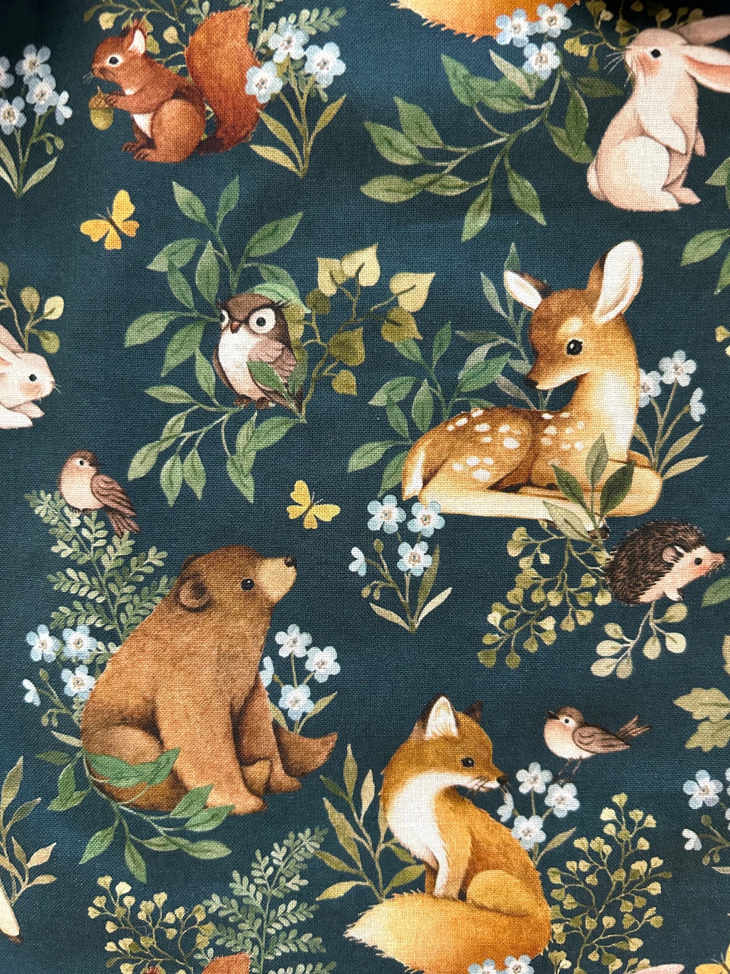 a close up of the fabric showing the deer, bear, owls, birds and branches