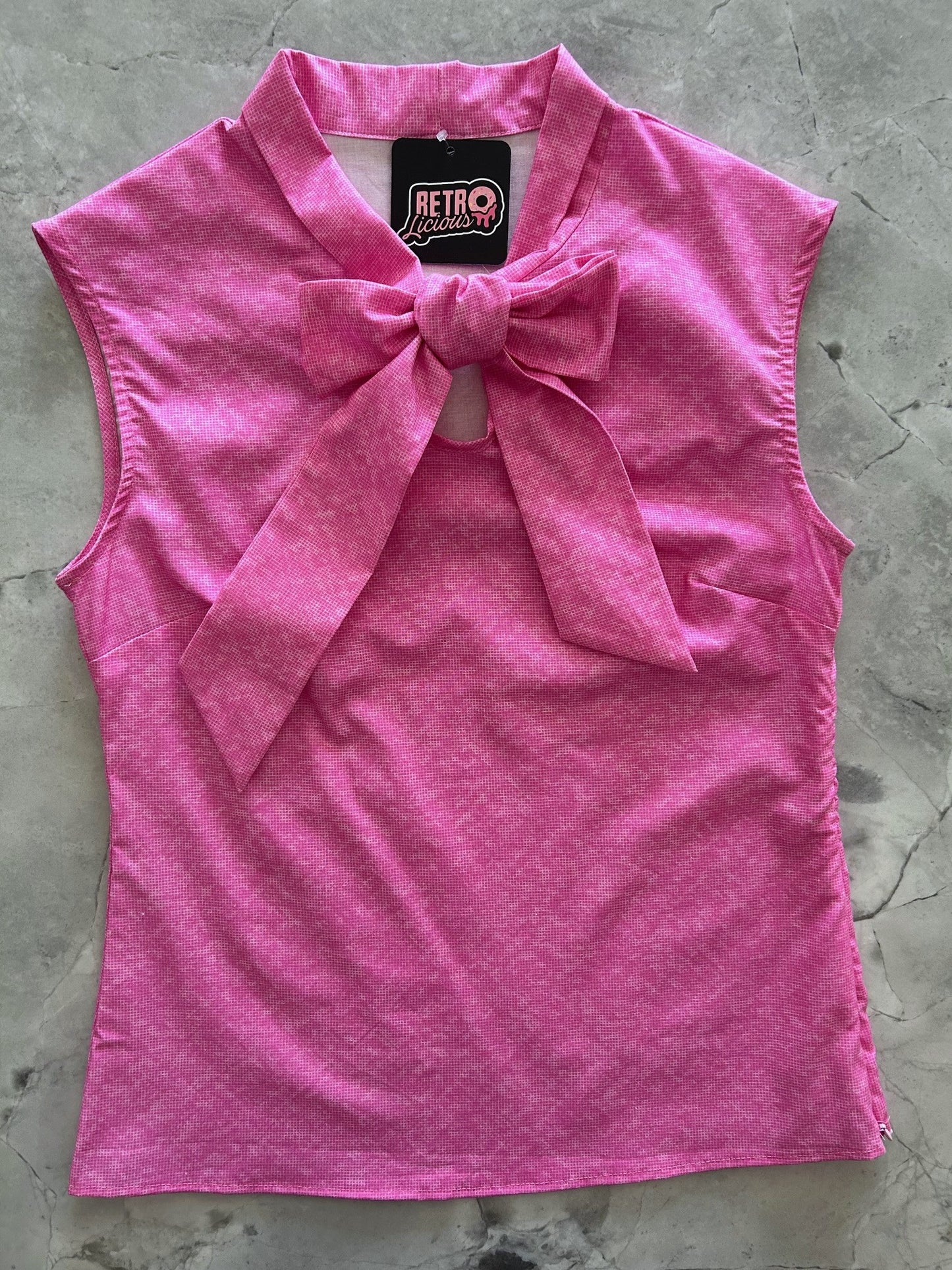 a flatlay of the front of the pretty in pink bow top