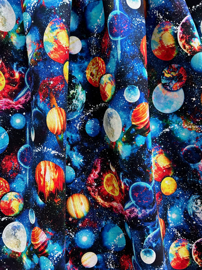 close up of fabric showing the colorful planets on navy background