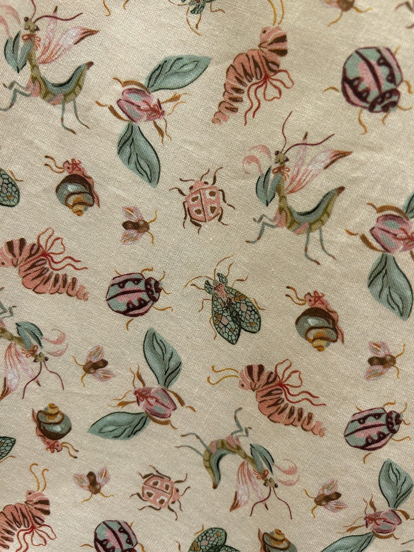 close up of bugs doris skirt fabric showing tossed bugs on peach background