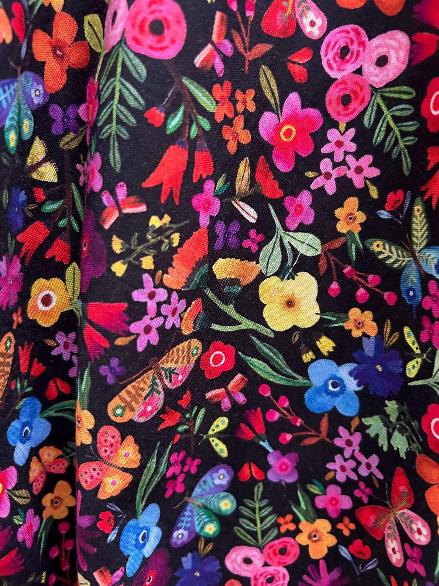 closeup of fabric showing colorful flowers and butteflies on black background
