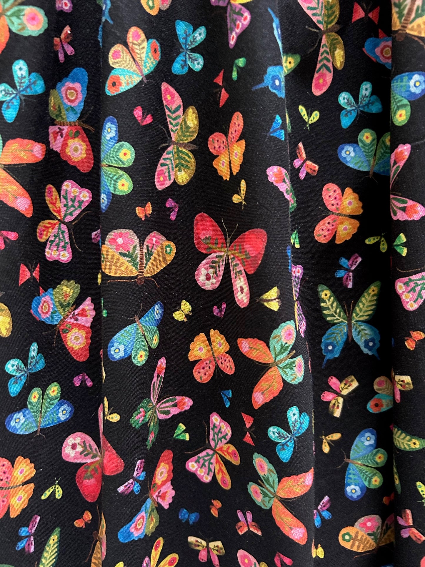 close up of fabric print showing colorful butterflies on black background
