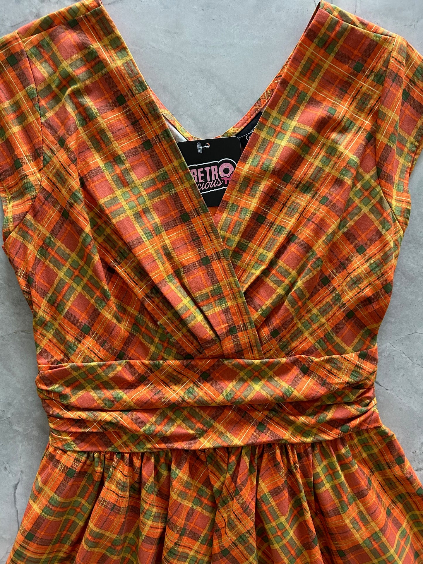 Plaid fabric with orange and green pattern on a gray surface