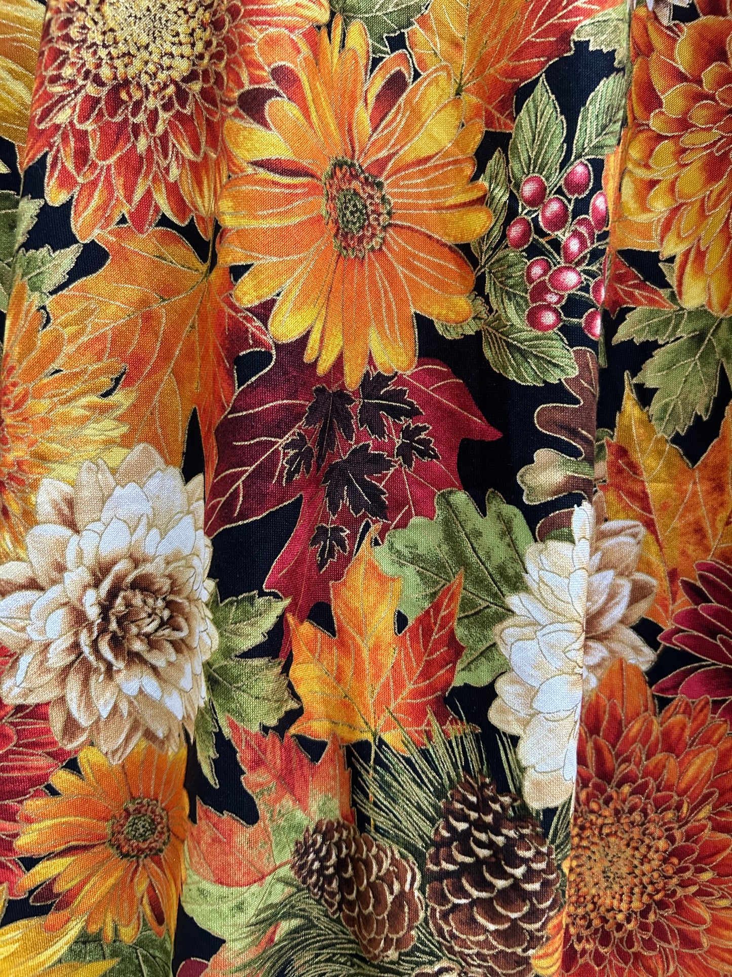 Colorful fabric with autumn-themed pattern featuring flowers, leaves, and berries.