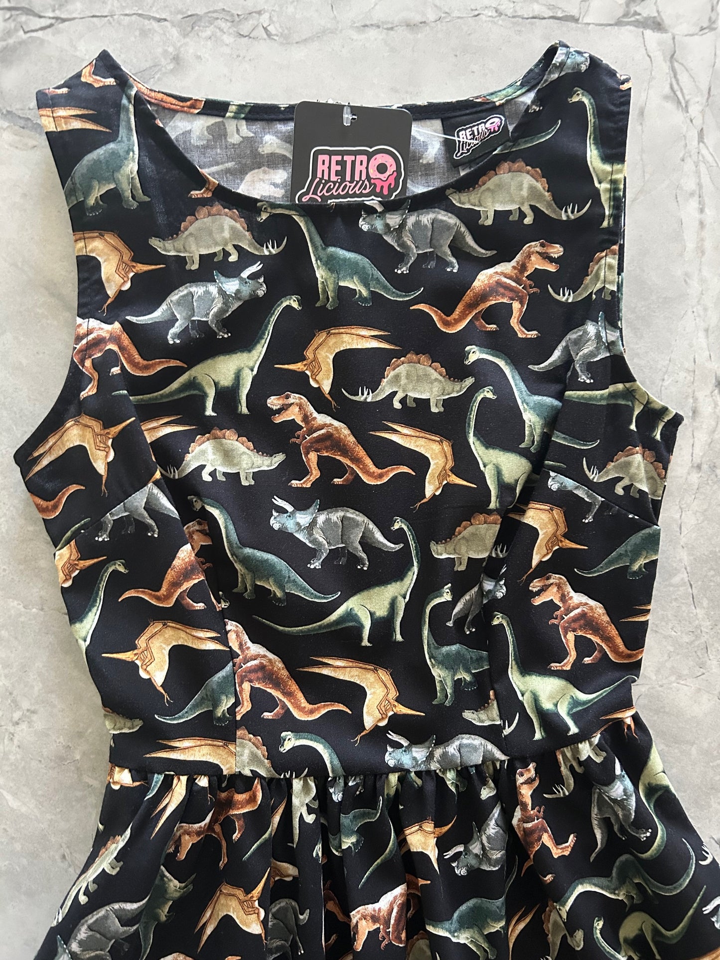 Dinosaur-patterned dress on a light gray surface