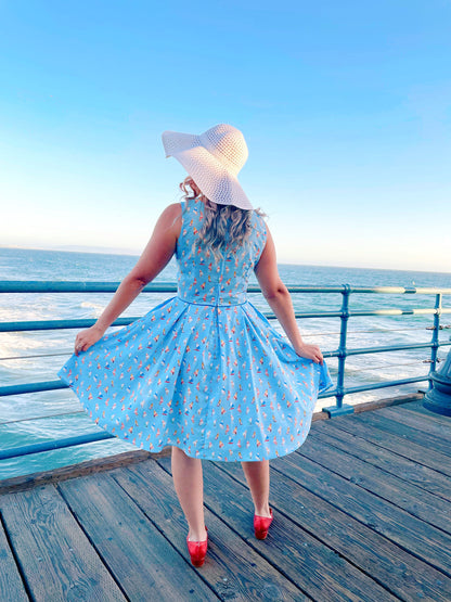 a back view of model standing on the boardwalk in front of the ocean wearing elizabeth dress in windsurfer and white sun hat
