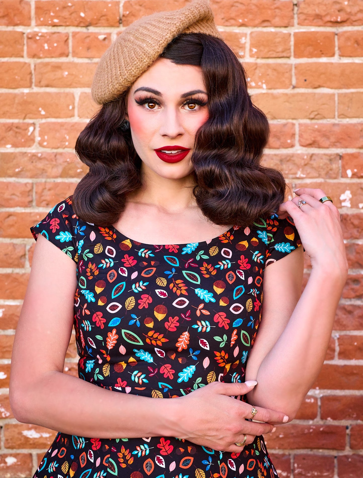 a close up of a model standing in front of brick wall wearing the leaves and acorn margaret dress and beret