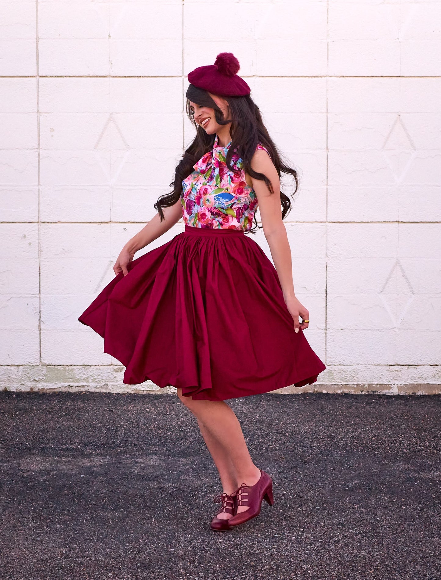 a full size image of a model standing in front of a white wall wearing the watercolor floral bow top