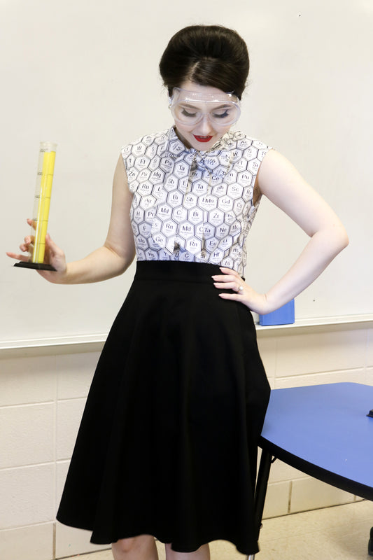 Person wearing a patterned top and black skirt holding a yellow container.