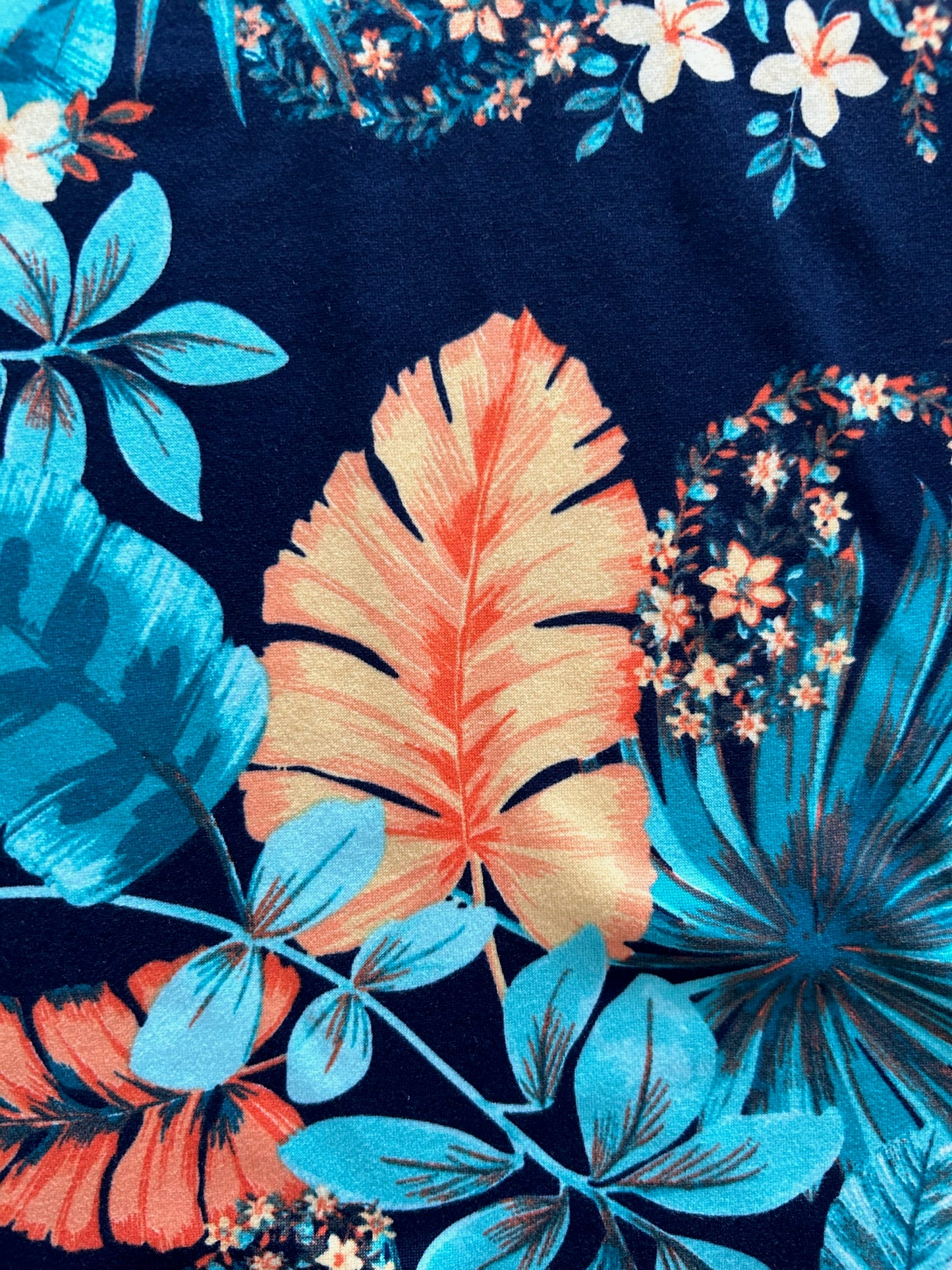 a close up of the isabel top in tropical fabric showing blue and orange leaves and flowers