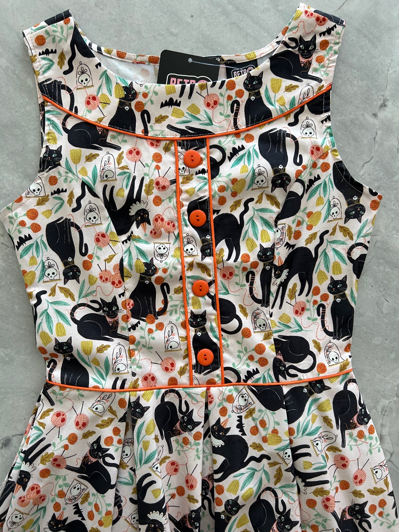 a close up of the bodice of Elizabeth dress in cats showing the orange buttons and piping detail
