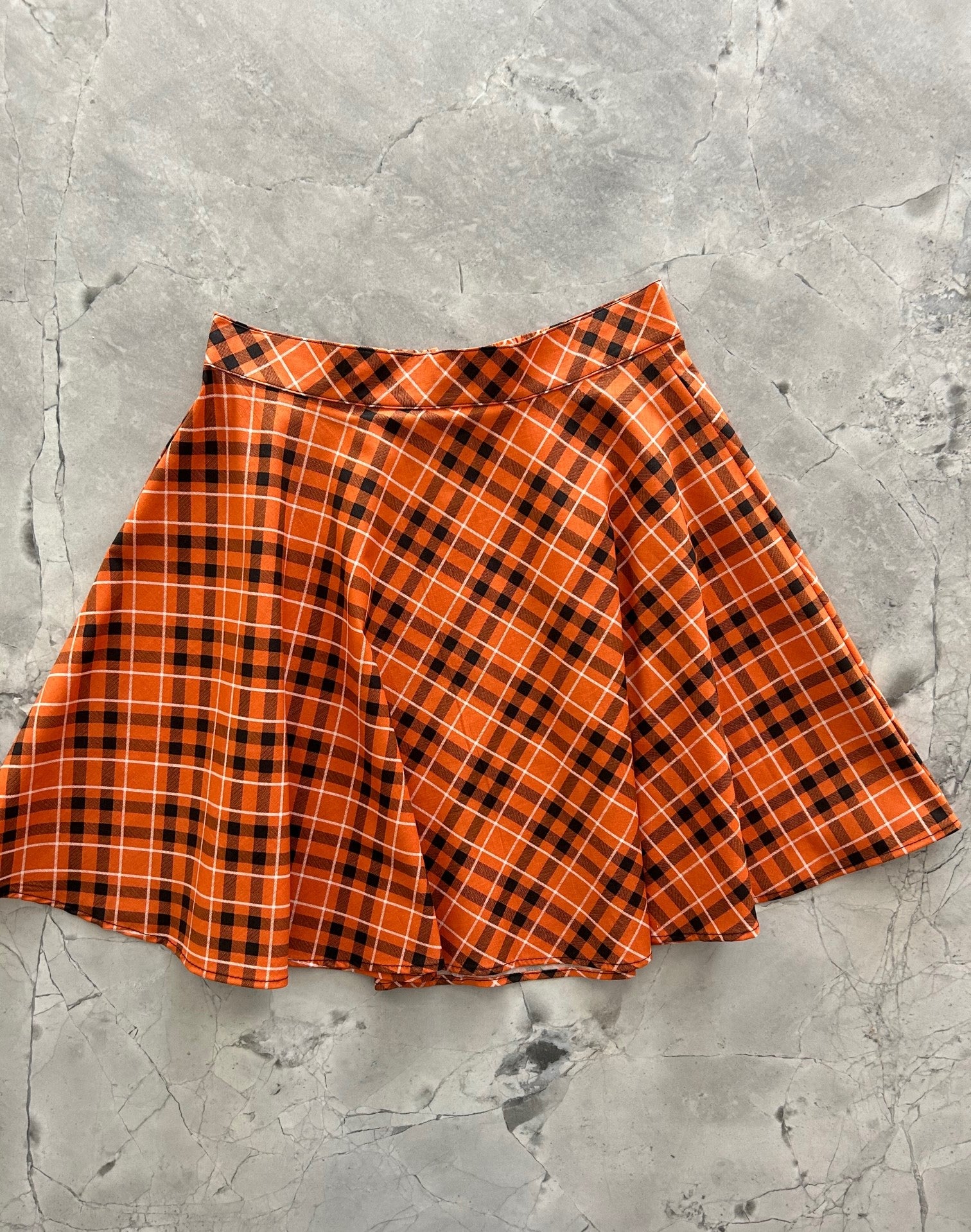 a flat lay image of the front of the orange plaid skater skirt
