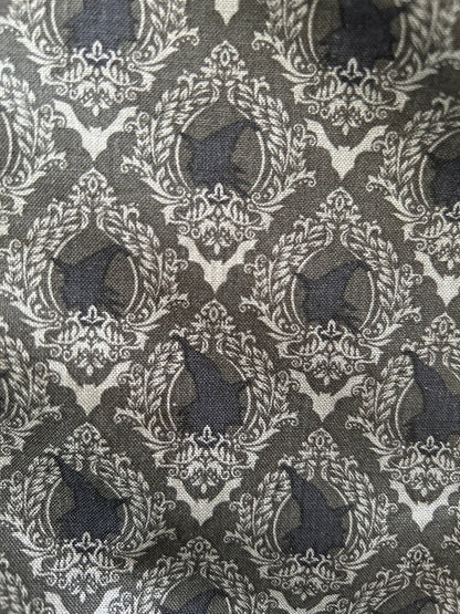a close up of the fabric showing the print with profile picture of witches in decorate frames in colors black and shades of grey