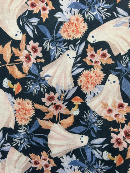 a close up of fabric swatch of the ghosts dress showing dancing ghosts and flower and mushrooms