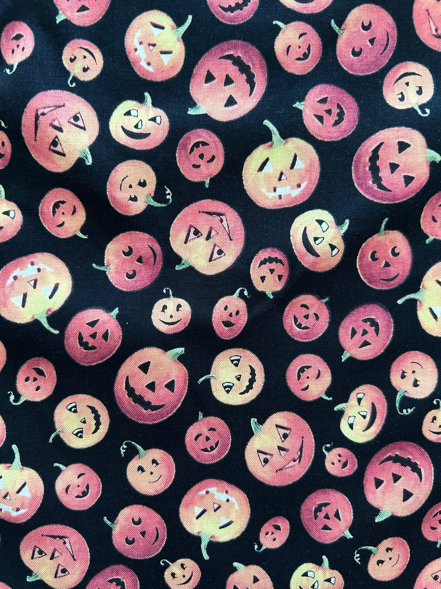 a close up of the fabric swatch showing the tossed print of jack-o-lanterns