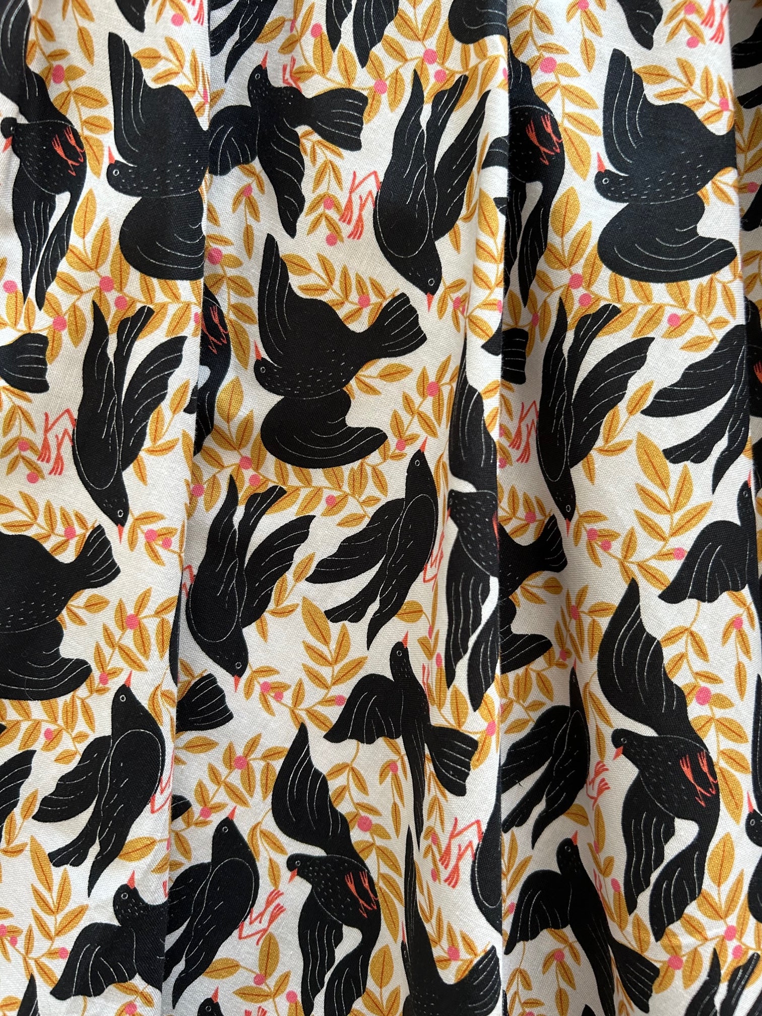closeu up of the fabric showing the black birds and mustard leaves