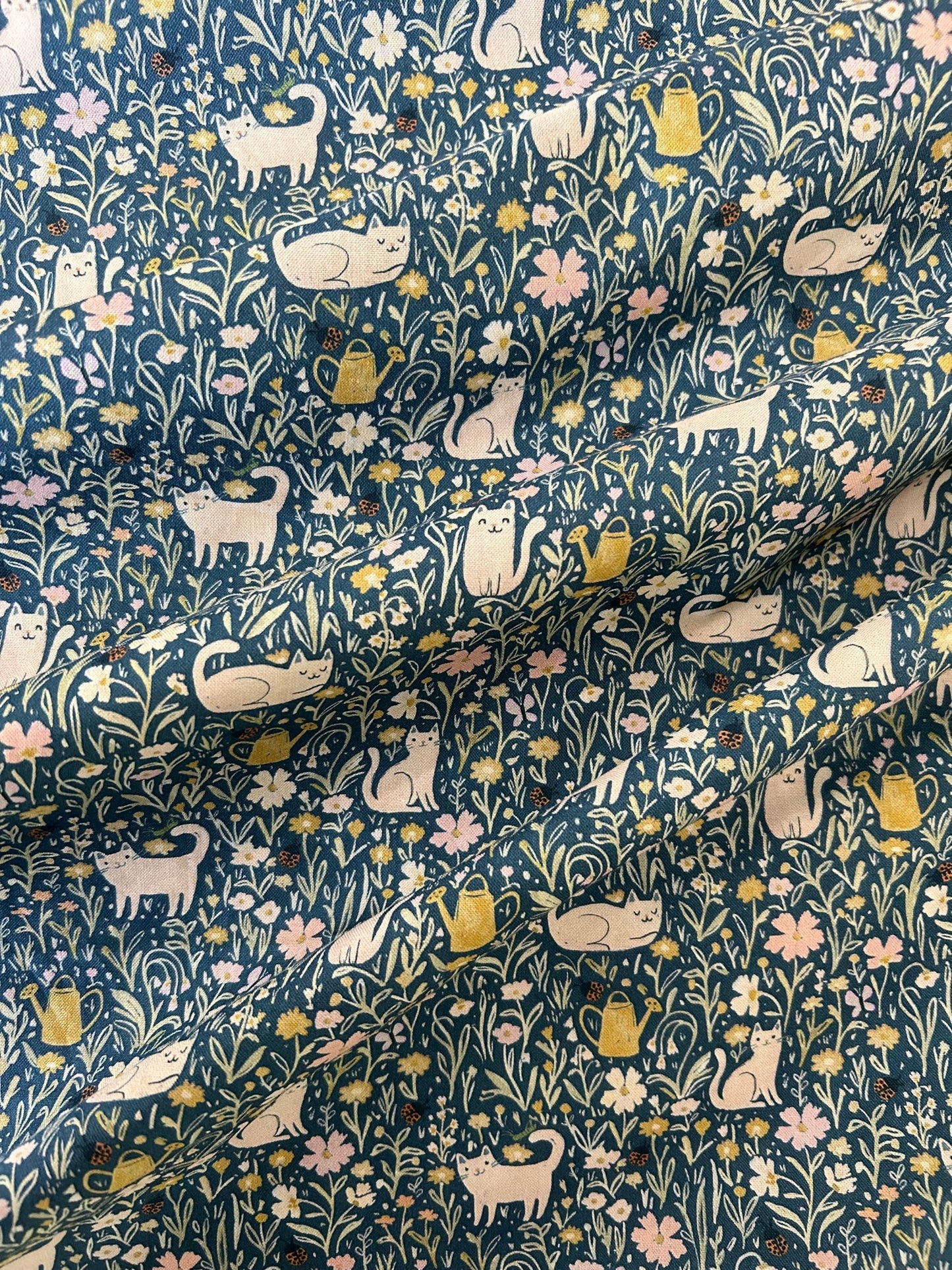 a close up of the fabric showing the pring of cats in fields of flowers