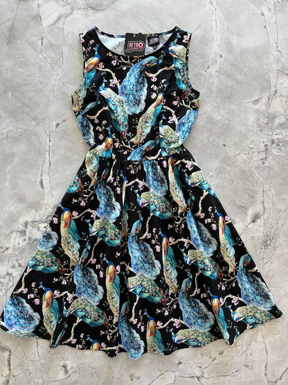 a flat lay of our peacock vintage dress with large scale peacocks all over on black bacground