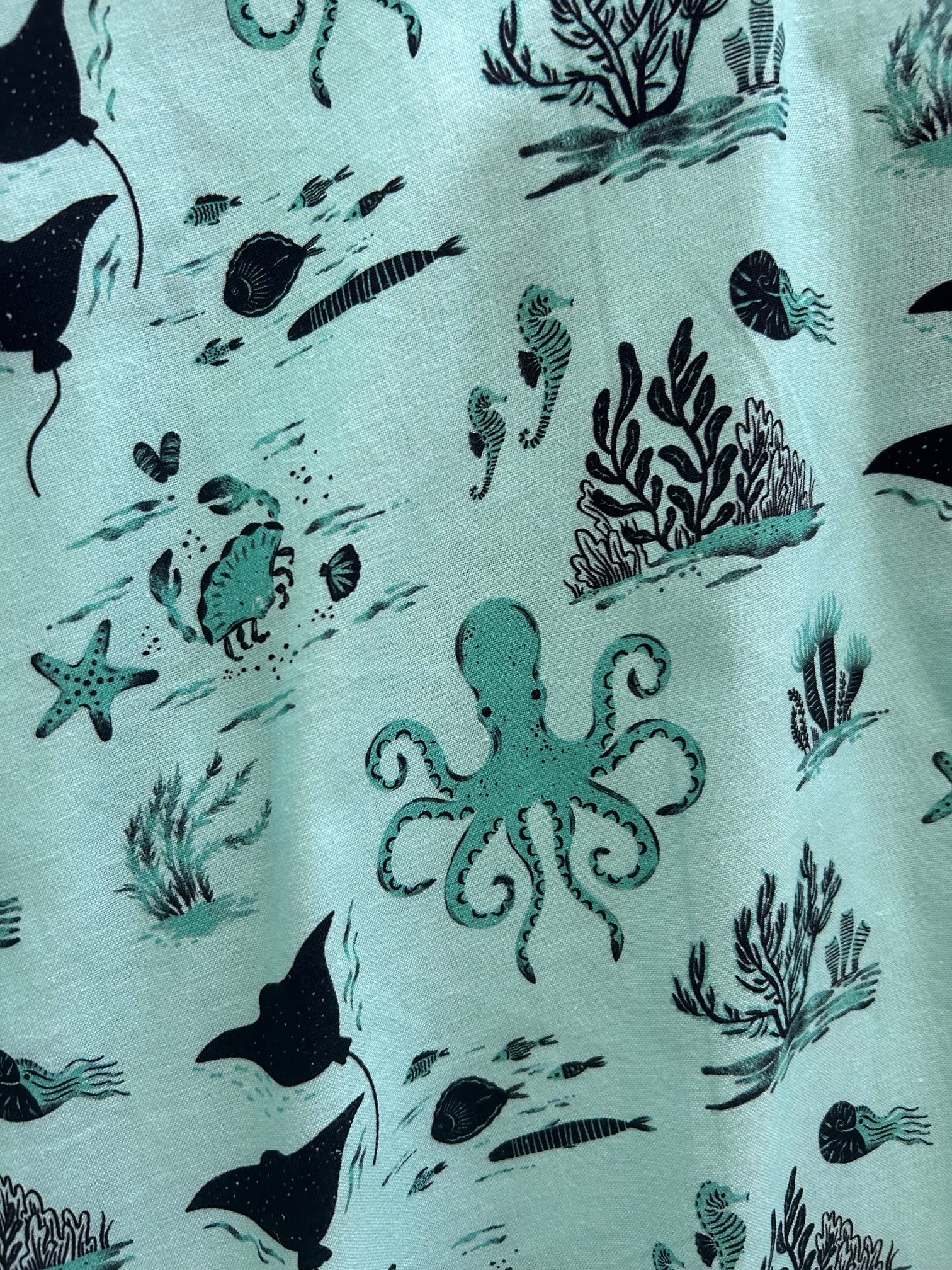 a close up of fabric print showing sea life like octopus, sea horse and fish