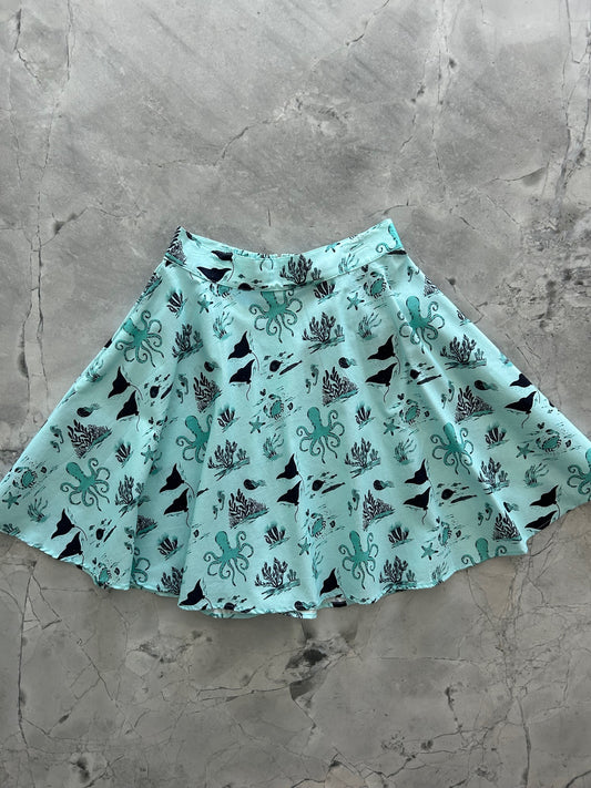 a flat lay of skater skirt with sea animal print on light blue background