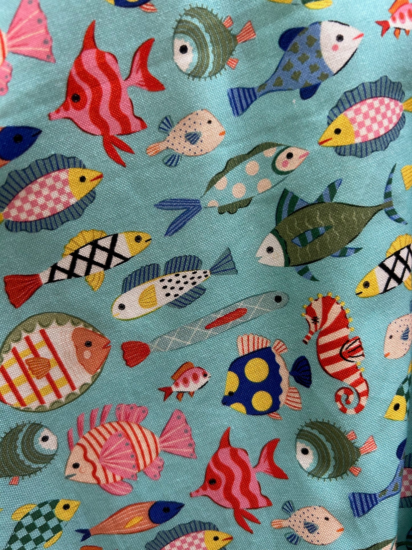 a close up of the fabric print showing details on the colorful fish on blue background