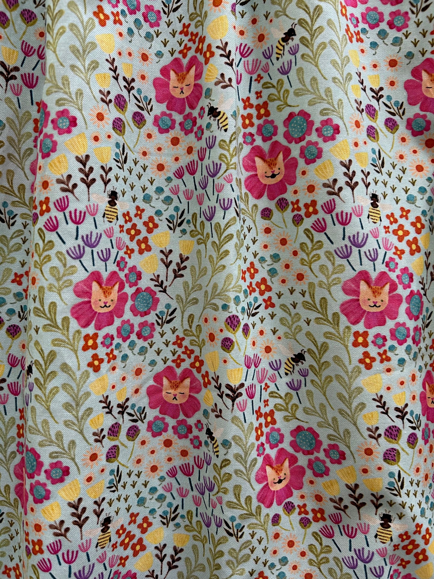 close up of fabric showing the cats and flowers print on light minty green background
