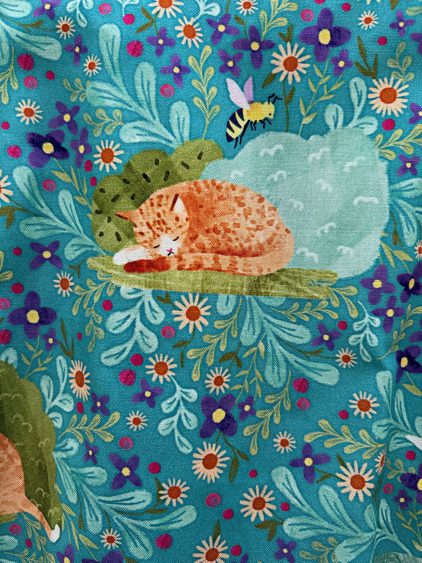 close up of fabric print showing a cat and the floral background