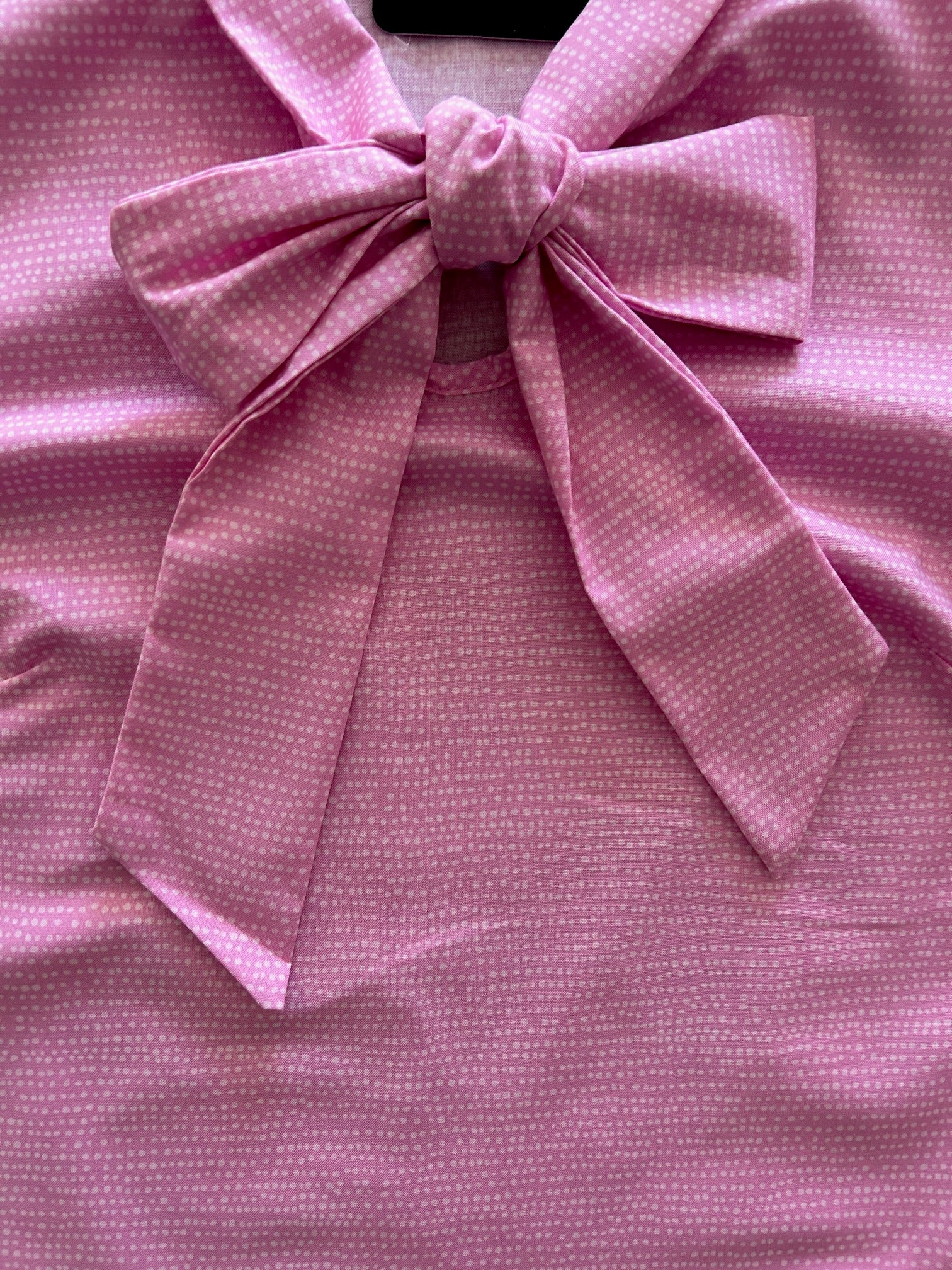 flat lay of pink dot bow top showing the front bow detail