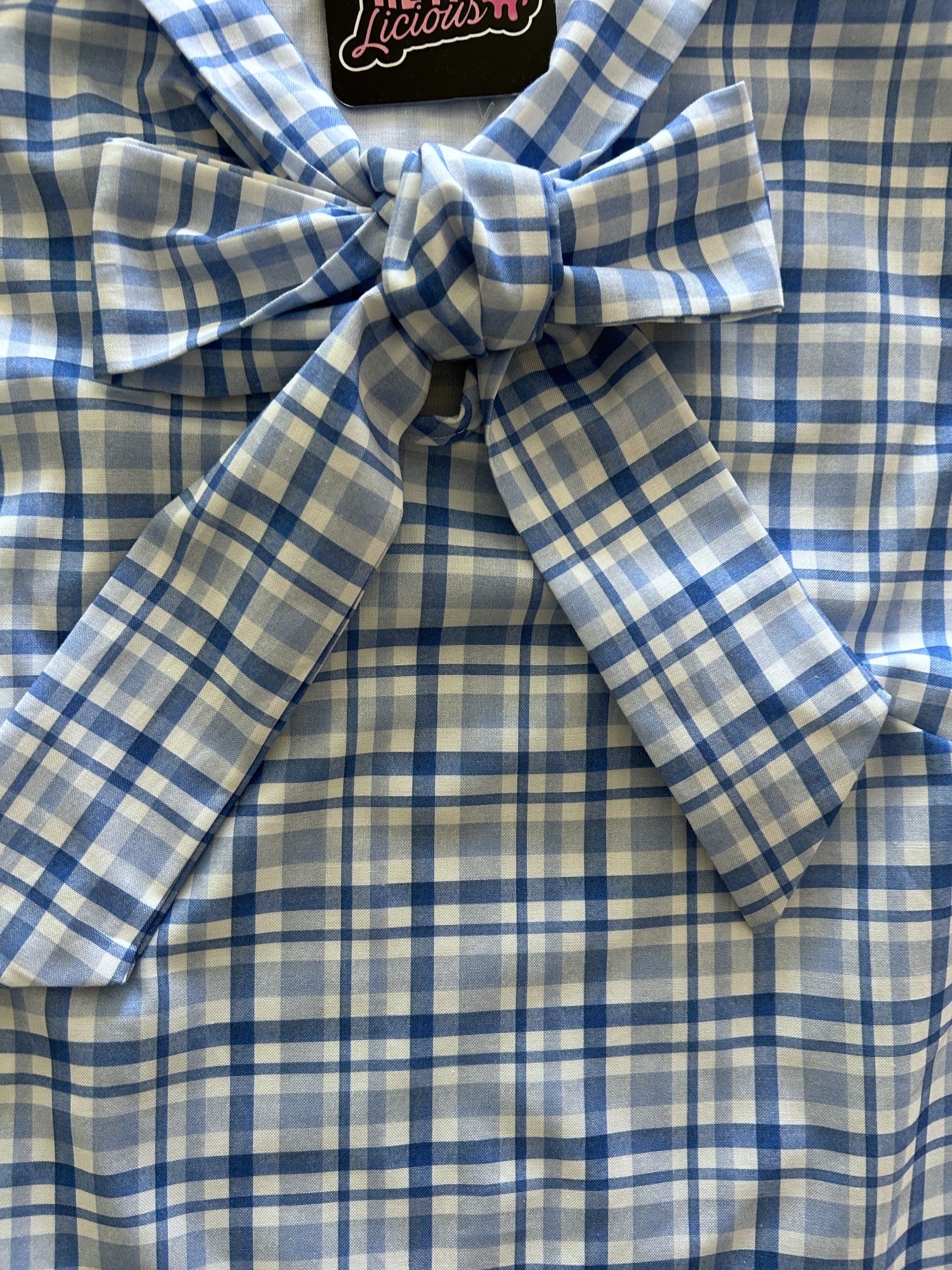 flat lay of blue plaid bow top with close up of front bow