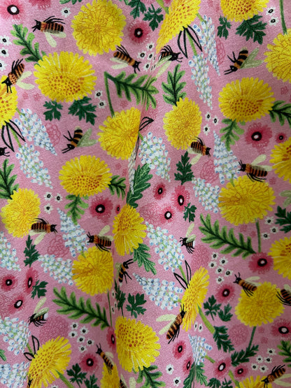 a close up of the fabric showing the flowers and bees on pink background