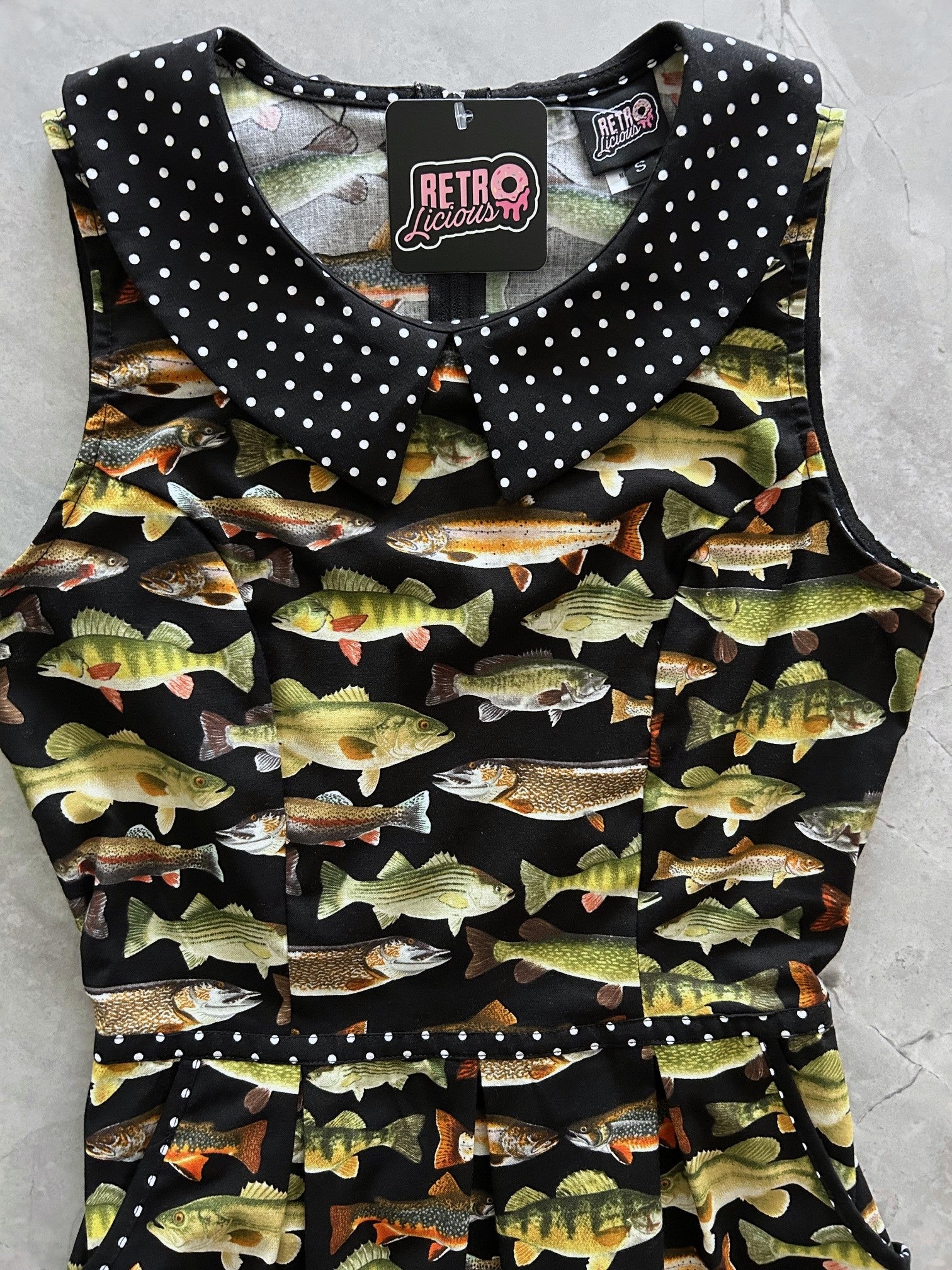 a close up showing the green fish on black background fabric and polka dot collar
