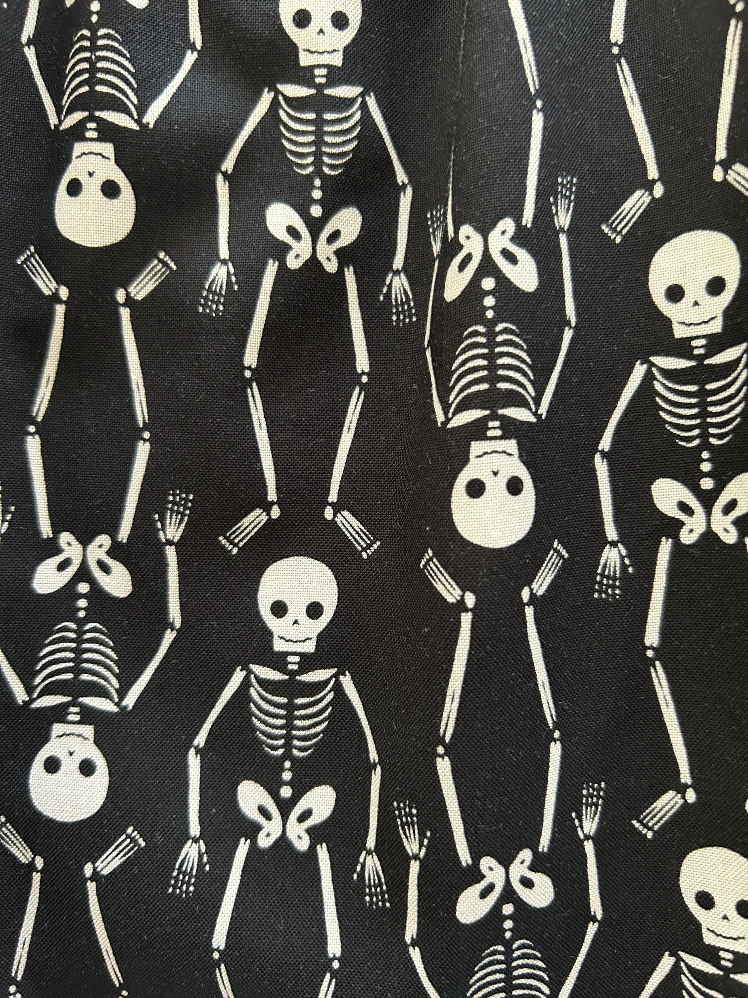 close up of fabric sowing the white skeletons on black bacground