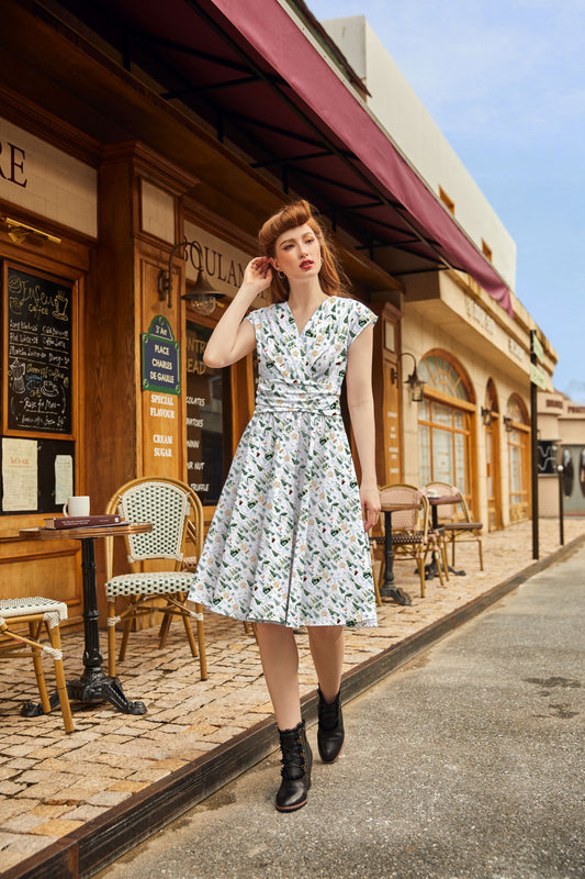 Woman in a floral dress standing on a street with a café in the background