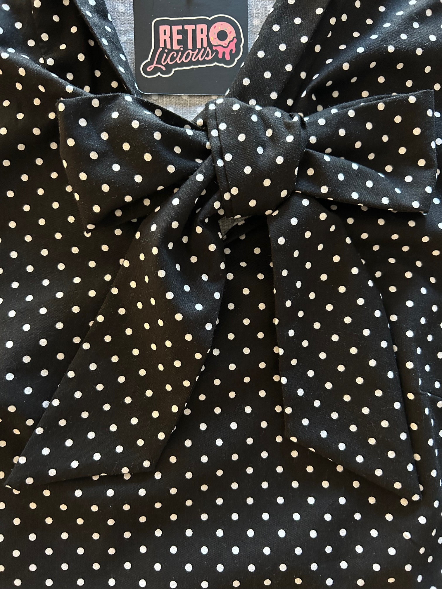 flatlay of black polka dot top showing close up of bow