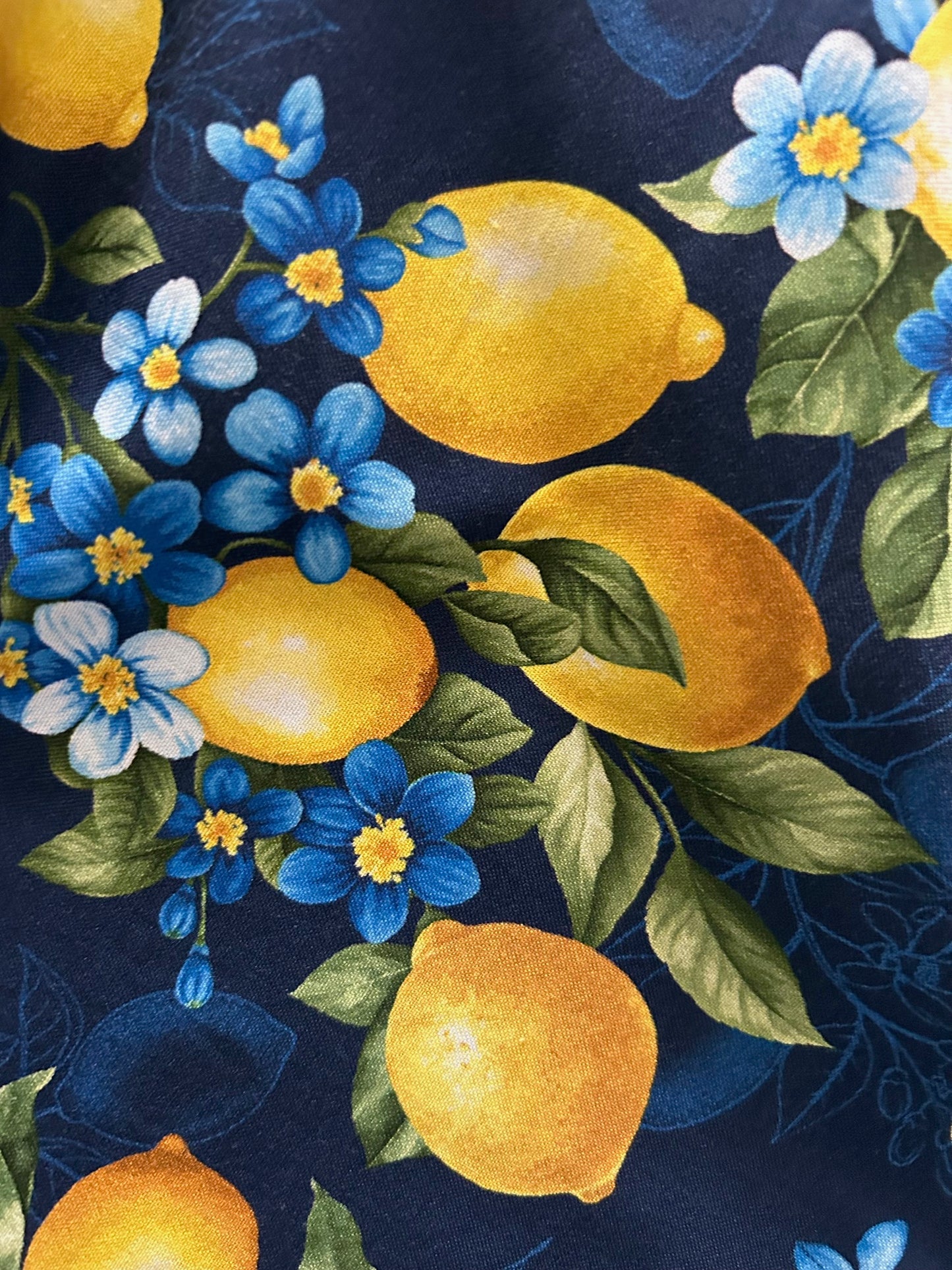 close up of print showing lemons on a branch with blooms on navy background