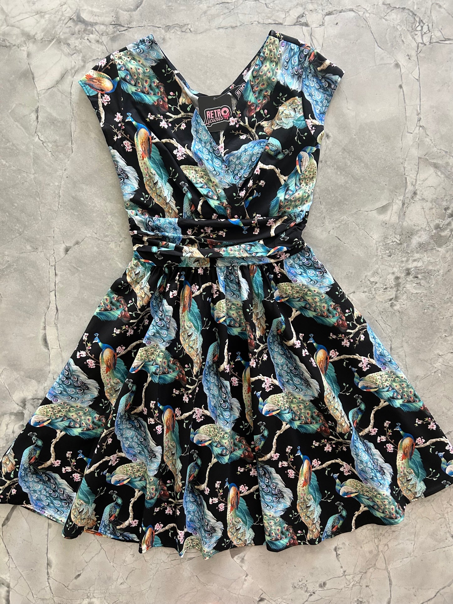 flatlay of peacock on branches greta dress