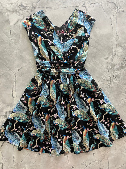 flatlay of peacock on branches greta dress