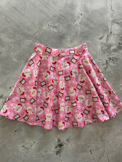 flatlay of pink background with tossed santa heads and hot cocoa skater skirt