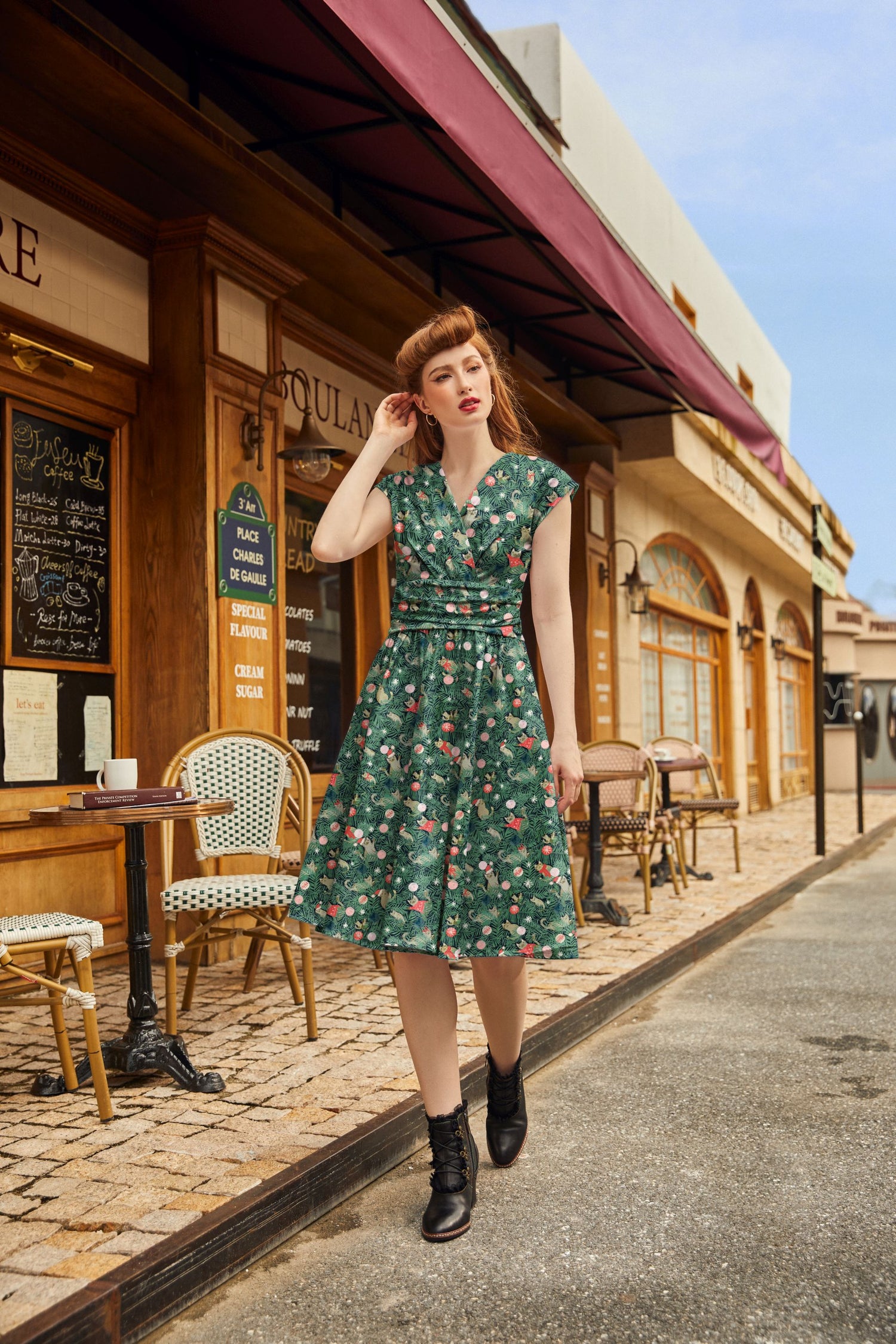 Woman in a green  dress standing on a street with a café in the background