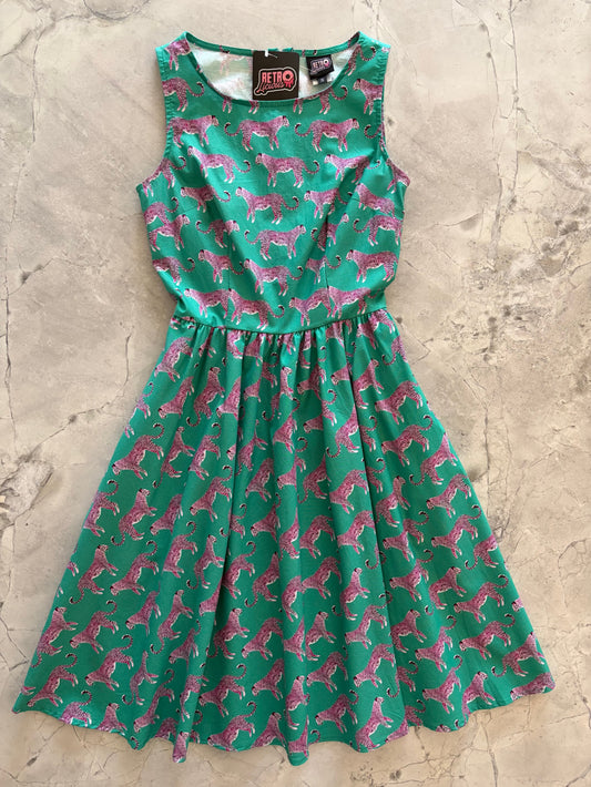 Green dress with pink dog pattern on a textured beige surface