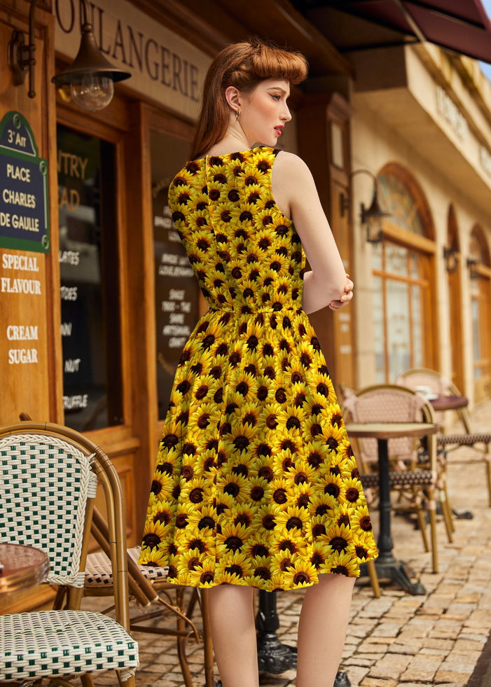 Woman wearing a yellow dress with black floral pattern in an outdoor cafe setting