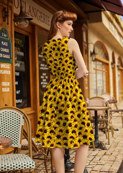 Woman wearing a yellow dress with black floral pattern in an outdoor cafe setting