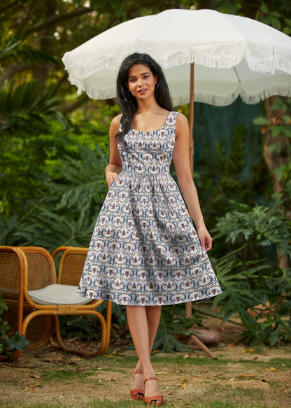 Woman in a floral dress holding a white umbrella in a garden setting