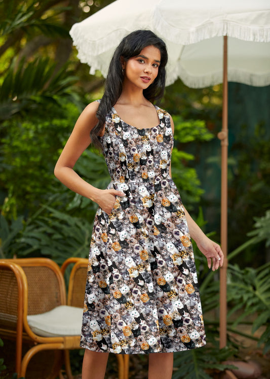 Woman wearing a floral dress standing outdoors with greenery and an umbrella in the background