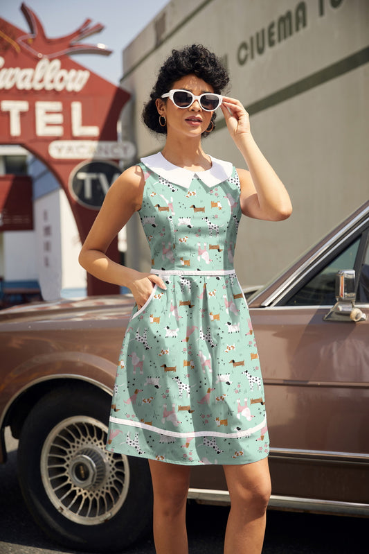 Woman in a vintage-style dress standing in front of a classic car and motel sign.