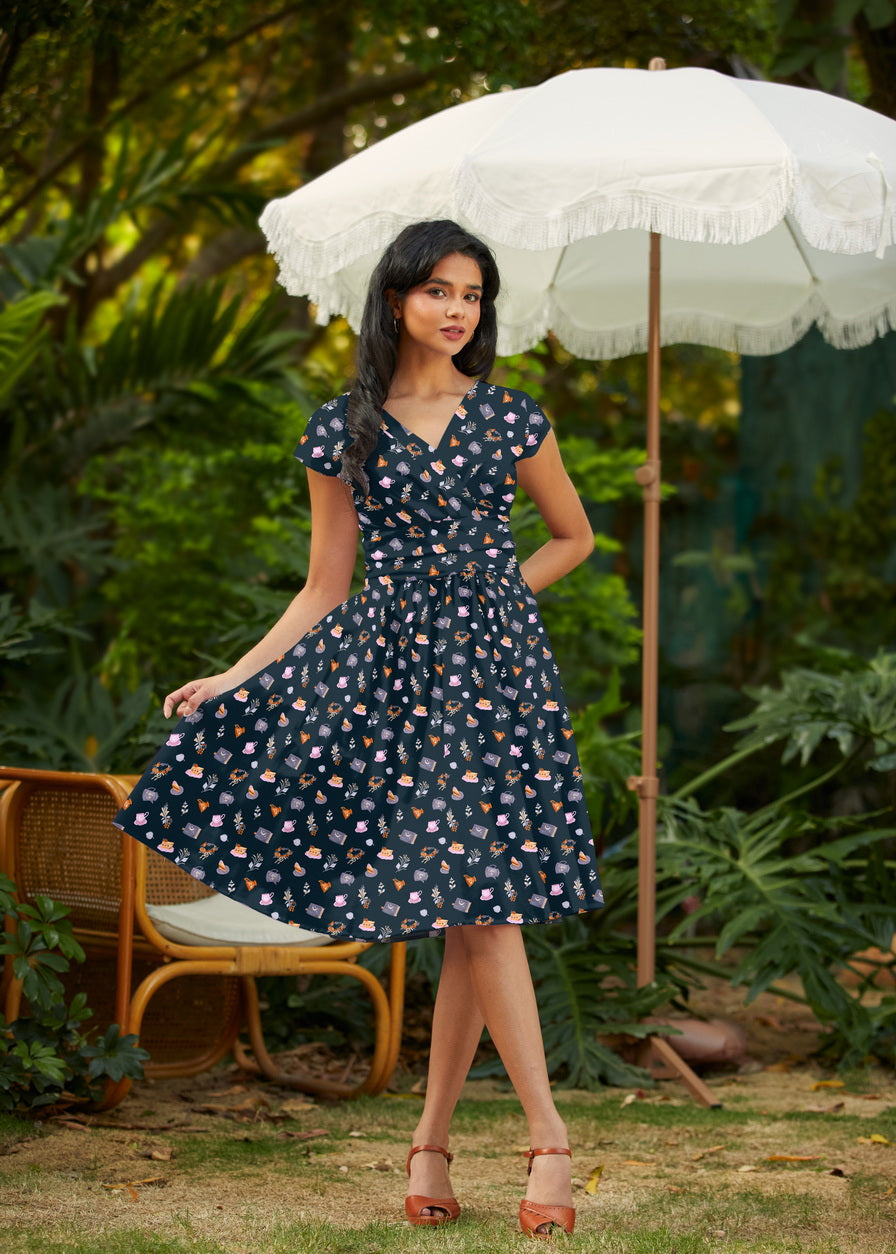 Woman in a navy floral dress holding a white umbrella in a garden setting