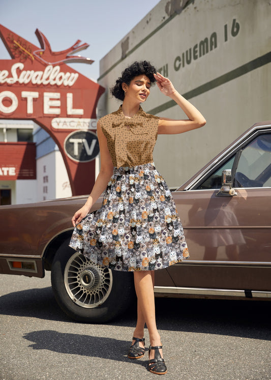 Woman in a vintage dress standing next to an old car with a motel sign in the background